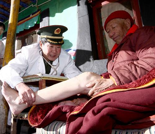 1月8日,西藏军区总医院院长李素芝(左)在拉萨曲桑寺为江白活佛检查腿疾。李素芝长年带领医务官兵深入边远牧区、雪山、寺庙,为各族群众防病治病、送医送药,为构建和谐西藏作出了巨大贡献,被国务院授予“全国民族团结进步模范个人”等众多荣誉称号。 新华社记者 陈建力 摄