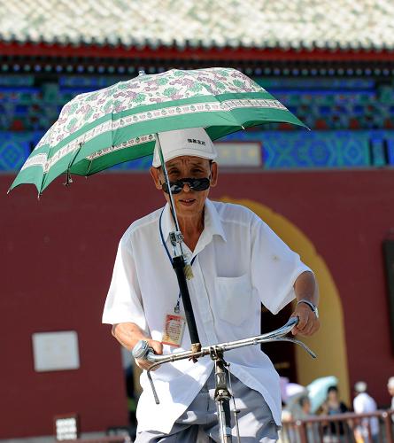6月24日,一位老人在自行车上安装了一把遮阳伞在北京街头骑行。当日,北京的最高气温升至37℃以上,北京市气象台将高温预警信号由黄色升级为更高级别的橙色。气象专家提醒市民,要尽量避免在强烈阳光下进行户外活动,特别是午后高温时段要避免长时间在阳光下暴晒,同时采取防晒和降暑措施。 新华社记者 李文 摄