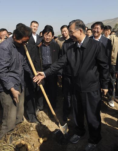 10月17日,温总理来到凤翔镇南川万亩马铃薯基地,查看生产和收获情况。庄稼地里,人们正忙着挖土豆。温家宝走进地里,从村民郭涛手里接过铁锹,一锹下去翻出来5个土豆。拿起亲手收获的土豆,温总理详细询问郭涛,他种了多少亩土豆?亩产多少斤?一亩收入多少?温总理把铁锹还给郭涛后,向他伸出右手要和他握手告别。郭涛躲闪着说,我手上都是土,脏。温总理说,我手上也有土,没关系。新华社记者 李学仁 摄