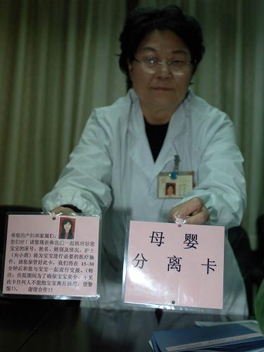 12月3日,西安交大一附院妇产科主任苟文丽在展示医院设计的“母婴分离卡”的正面和反面。该卡用于从产妇处临时抱走婴儿的各种医疗活动。 新华社记者 丁海涛 摄
