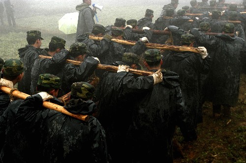 2月17日,解放军官兵冒着雨雪将电线杆抬上山。当日,成都军区某部百名官兵在贵州省黔东南州三穗县抢修遭受凝冻灾害的青穗输电主干线。这条线路是三穗县连接国家电网的主要通道。 新华社发(黄震 摄)
