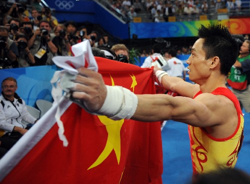 8月14日,中国选手杨威在夺冠后手持五星红旗庆祝。当日,在国家体育馆举行的北京奥运会男子个人全能决赛中,中国选手杨威以94.575分的成绩夺得冠军。 新华社记者程敏摄
