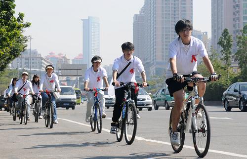 12月1日,暨南大学学生胸戴“红丝带”在广州街头参加骑车绕城宣传活动。当日是世界艾滋病日,各地举行防治艾滋病宣传活动,市民、学生、医护人员等各界人士广泛参与。新华社记者 卢汉欣 摄