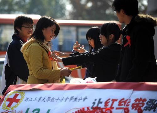 12月1日,浙江工业大学的学志愿者为同学戴上“红丝带”。当日是世界艾滋病日,各地举行防治艾滋病宣传活动,市民、学生、医护人员等各界人士广泛参与。新华社记者 徐昱 摄