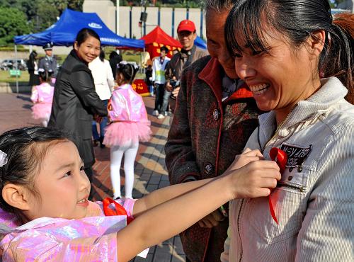 12月1日,在福州市五一广场艾滋病防治宣传活动现场,一名小女孩为市民戴上“红丝带”。当日是世界艾滋病日,各地举行防治艾滋病宣传活动,市民、学生、医护人员等各界人士广泛参与。新华社记者 张国俊 摄