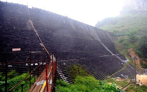 这是发生险情的卡马水库大坝(7月3日摄)。连日来,受强降雨影响,广西河池市罗城仫佬族自治县卡马水库水位急剧上涨,水库大坝放空导流洞出口右侧边墙部分被冲毁。出现险情后,河池市把7443名当地群众紧急转移到安全地带,目前,河池市正在组织武警官兵和当地干群全力抢修发生险情的卡马水库。国家防汛抗旱总指挥部也已派出8名专家协助开展抢险工作。卡马水库集雨面积52.3平方公里,总库容930万立方米,大坝全长250.3米,最大坝高38.7米。新华社记者 张爱林 摄