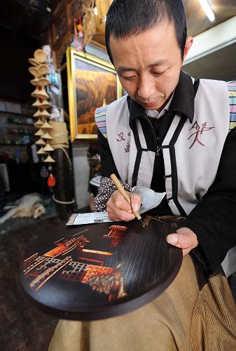 一位手工艺人在云南丽江古城的店铺内制作东巴盘,准备供应旅游市场(9月29日摄)。国庆长假将至,气候宜人、风光旖旎的云南丽江成为国内外游客理想的旅游目的地。加之大理至丽江铁路已于9月28日正式通车,丽江旅游不断升温。新华社记者 蔺以光 摄
