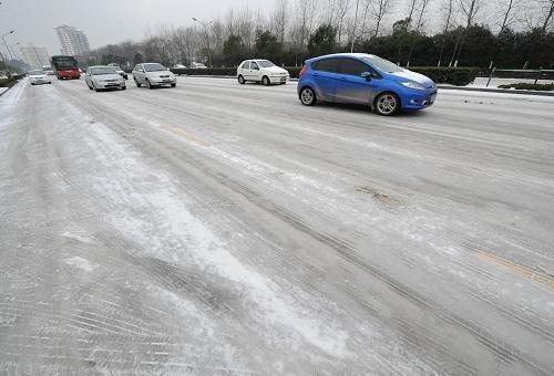 2月11日,汽车在南京市区积雪结冰的道路上行驶。当日,南京出现降雪和低温冰冻天气,江苏省气象台发布道路结冰橙色预警。目前,因路面积雪结冰,南京周边高速公路封闭,长途车站大批旅客滞留。新华社记者 孙参 摄