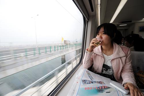 4月26日,在福厦铁路运行的首趟和谐号动车上,一位乘客在欣赏沿途风景。当日,总投资152.59亿元、全长274.9公里的福(州)厦(门)高速铁路正式开通运营。这条铁路的通车运营,使福厦之间铁路运行时间从原来中转绕行所需的11个小时缩短到目前的1.5个小时。新华社记者 张国俊 摄