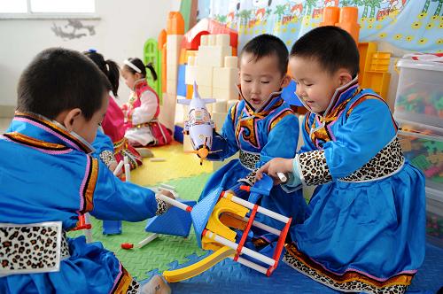 5月6日,内蒙古自治区鄂尔多斯市伊金霍洛旗霍洛镇幼儿园的孩子巴特(右一)和小朋友们一起上手工劳动课。从2010年开始,内蒙古鄂尔多斯市在落实国家确保义务教育经费机制的前提下,对全市的蒙古族学生3年幼儿园、6年小学、6年中学直至4年大学本科毕业,实行19年的免费教育。目前鄂尔多斯市除了对幼儿园的蒙古语授课幼儿每人每月免除240元的保教费、读物费外,还每月补助120元伙食费;对中学生除“两免一补”外,每年还补助200元交通费,并且减免中考、高考考务费;对考取专科、普通本科和国家重点本科院校的蒙古族学生,每人每年分别提供3000元、5000元和7000元的补助费。新华社记者 张领 摄