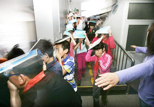 5月11日,在北京府学小学举行的防灾演练中,学生们在教师的引导下有序“逃生”。在5月12日第二个国家“防灾减灾日”到来之际,各地中小学纷纷在校园内举行防灾减灾演练,旨在增强师生们的防灾减灾意识并提高应急自救知识技能。新华社发(张传东 摄)