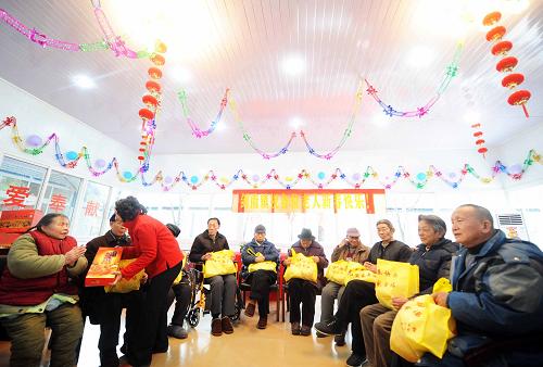 1月25日是农历除夕,在四川地震重灾区绵竹市剑南镇紫岩社区板房敬老院,有关方面领导在向因地震致孤致残的老年人赠送礼品。 新华社记者 李晓果 摄