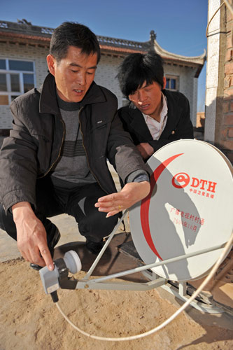 宁夏银川市永宁县文化旅游广播电视局工作人员(左)向村民讲解卫星电视使用方法(2月22日摄)。新华社记者 王鹏 摄