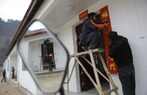 1月25日,陕西省略阳县郭镇街村安置点的村民在贴春联。春节临近,陕西省略阳县郭镇街村安置点的村民忙着挂灯笼,贴春联,红红火火地迎接新年的到来。虽然村民的房屋在地震灾害中倒塌,但是在春节前,他们搬进了集中安置点的新房。村民们盼望着春暖花开,把没有完工的厨房修完,安置点里的道路平整好,共同迎接美好的明天。新华社记者 邢广利 摄