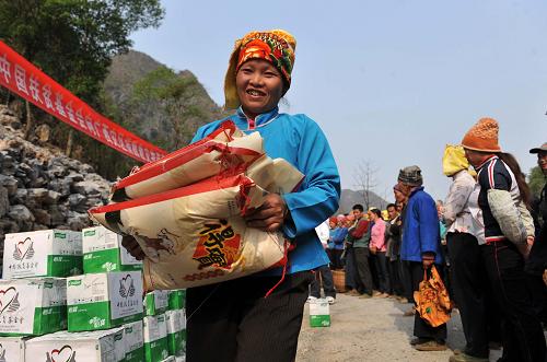 3月27日,在广西百色市凌云县泗城镇后龙村,一名瑶族妇女在领取大米。新华社记者 周华 摄
