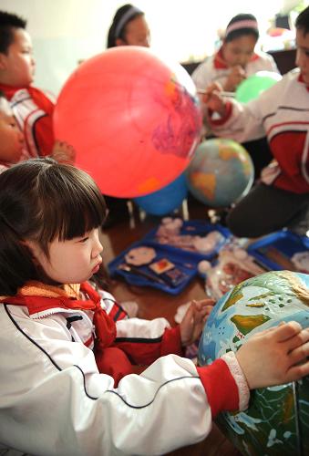 4月22日,几名学生正参考地球仪在气球上绘制图案。新华社记者 王菲 摄