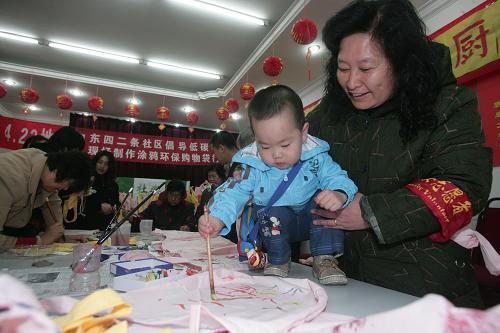 4月22日,在北京市东城区东四二条社区,一名年龄最小的参与者在环保袋上涂鸦。新华社发(郝飞 摄)