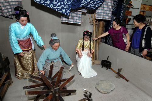 6月1日,几位游客在参观“元代棉纺织家黄道婆劳动场景再现”。新华社记者 丁海涛 摄