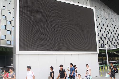 8月15日,参观者从上海世博园市民广场大屏幕前经过。新华社记者 汪永基 摄