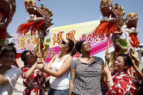 5月1日,一支老年舞蹈队的队员教几名外国游客舞龙灯。新华社记者 裴鑫 摄