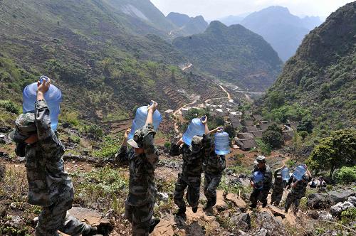 3月31日,在广西那坡县百南乡弄民村三支屯,解放军官兵在崎岖的山路上运水。当日,记者随广西那坡县百南乡弄民村三支屯村民和解放军驻地官兵亲历运水路,用镜头记录下他们取水的艰辛和军民间的鱼水深情。三支屯是一个在大山深处的村屯,村庄背后就是越南。持续的干旱让这个边境村屯严重缺水,因地处偏远,道路崎岖,村民们每天要往返3次、每次历时近3个小时到政府在弄民村修建的水池取水。为保证村民用水,当地政府将水送到离三支屯最近的地方,驻地解放军官兵则和村民一道将水运进村屯。新华社记者 周华 摄