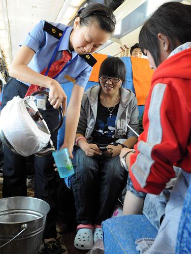 7月4日,被藏族群众称为“格桑花”的列车员魏若思在唐古拉段为旅客送水。从2006年7月1日青藏铁路全线通车到今年7月1日,北京铁路局北京客运段京藏车队4年中安全运行1168万公里,运送旅客438万人次,从未发生一起因安全和服务而起的旅客投诉事件。北京客运段京藏车队所值乘的T27/28次列车,从北京至拉萨全程4064公里,单程运行约46小时。在青藏铁路线上,京藏车队15个班组、500多名乘务人员克服高寒缺氧等困难,热情为广大旅客服务,先后推出了汉、藏、英三种语言服务,10多种藏、回菜肴以及介绍高原风光,向旅客发放服务新名片等方面的13项服务内容。在这条世界上海拔最高的铁路上,大多数的乘务人员跟车整整跑了4年。4年跑了100多趟,总计上万小时,架起民族团结的桥梁。新华社记 唐召明 摄