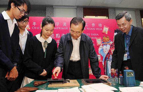 11月14日,国务院总理温家宝来到澳门博物馆,同在这里参观学习的学生们亲切交流。这是温家宝与学生们一起动手印制年画。新华社记者 饶爱民 摄