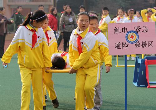 11月29日,在南通第二附属小学开展的应急联合演练活动中,一位“伤员”经过包扎后被同伴送往“安全地带”。新华社发(黄哲 摄)