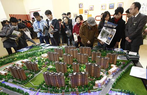 市民正在上海之春房展会上参观楼盘模型(2010年3月18日摄)。1月27日,备受关注的上海房产税试点细则“浮出水面”。上海市人民政府当日印发《上海市开展对部分个人住房征收房产税试点的暂行办法》,于28日起对上海居民家庭新购第二套及以上住房和非上海居民家庭的新购住房征收房产税,税率因房价高低分别暂定为0.6%和0.4%。新华社记者 裴鑫 摄