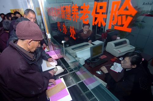 2月8日,在安徽合肥市肥东县撮镇农村合作银行内,农民正在凭借新型农村社会养老金存折提取保险金。新华社记者 郭晨 摄