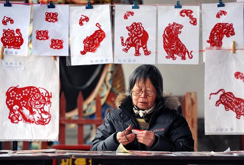 2月15日,在郑州春节文化庙会上,一位民间艺人在现场制作老虎图案的剪纸作品。春节期间,郑州城隍庙举办了以民俗表演、民间工艺品展示为主要内容的春节文化庙会,游客和市民在观赏传统“绝活儿”、选购民间“玩意儿”的同时增长民俗文化知识。新华社记者 王颂 摄