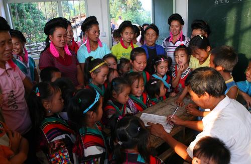 8月31日,在广西融水苗族自治县白云乡大坳瑶寨小学,红瑶女童在大人的陪伴下到学校报名。新华社发(龙涛 摄)