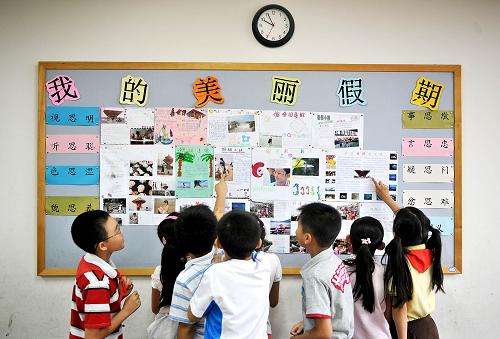 9月1日,在北京第二实验小学本校,暑假后重逢的同学们兴致勃勃地欣赏各自制作的假期生活小报。当日,全国中小学新学年开学。新华社记者 吴晓凌 摄