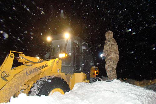 12月15日凌晨,救援人员利用大型机械清除积雪,打通救援道路。新华社发(张伯东 摄)