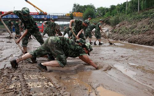 7月23日,参与救援工作的武警北京总队某部官兵在进行清理淤泥工作。 新华社发(李光印 摄)