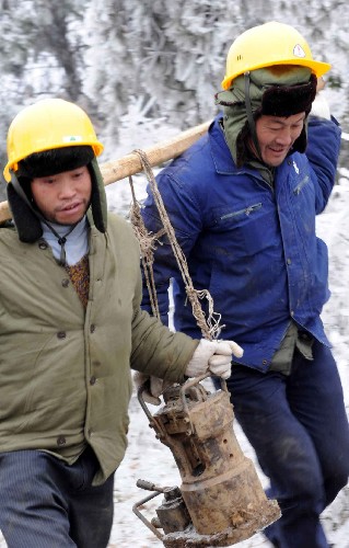 1月31日,在贵阳市水口寺的一条因雪凝灾害造成的220千伏安输电线路损毁现场,南方电网公司贵州送变电的两名抢险人员正在运送抢修设备。 新华社记者 杨楹 摄