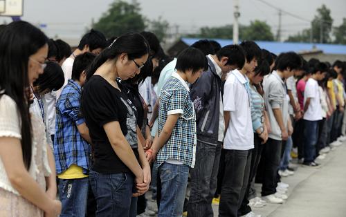 2009年5月11日,在德阳市东汽中学的临时板房教学点,师生们在升旗仪式默哀,纪念在大地震中遇难的师生。 新华社发