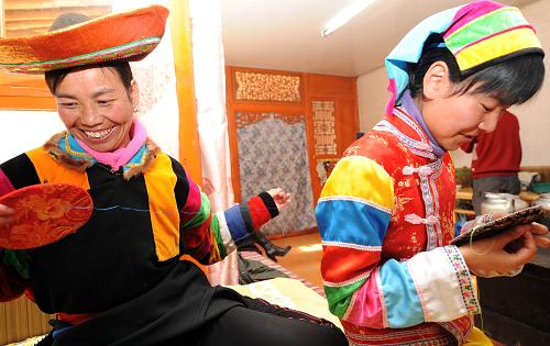 小庄村的土族姑娘祁兴芳(右一)在自家办起的民俗旅游接待点做土族刺绣(1月8日摄)。10年前,青海省互助土族自治县威远镇小庄村只是地处高原山乡的一个贫穷的土族小村庄,以农业为主业,全村人均收入不足600元。西部大开发以来,小庄村在当地政府的帮助与扶持下,利用丰富的民俗文化旅游资源和交通区位优势,大力发展土族民俗旅游业,土族歌舞、轮子秋、青稞美酒等旅游内容吸引了众多国内外游客前来参观体验。如今,全村100多户人家已发展民俗旅游经营户超过40户,95%以上的村民从事土族民俗风情旅游业,年人均收入超过4000元,其中旅游业收入占农民总收入的一半以上。新华社记者 侯德强 摄