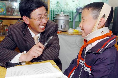 这是2005年4月30日,我国“希望工程”受助第一人——河北省涞源县桃木疙瘩村北京升旗希望小学教师张胜利(左)在给他的学生刘晓辉补课。新华社记者 杨世尧 摄