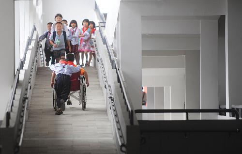 这是2009年9月1日,一位坐轮椅的少年被同学推着走在无障碍通道上。坐落在都江堰幸福镇的都江堰友爱学校是在国家和社会爱心人士悉心关怀下、在汶川大地震后建立的国内第一所全方位无障碍九年制义务教育示范学校,并被列入联合国教科文组织观摩的残疾人教育试点学校。120多名“折翅”少年被分到不同的班级,每班4至5人,与健康儿童一起,学习成长。新华社记者 江宏景 摄