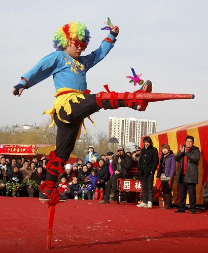 2月18日,正月初五,在第十届北京莲花池庙会上,民间艺人丁加伟表演踩高跷踢毽子。新华社发(李文明 摄)