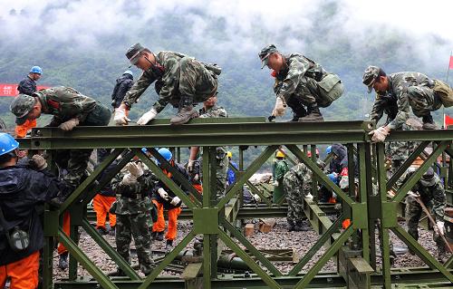 8月23日,武警官兵和公路部门的工作人员在加紧架设钢架桥。新华社记者 蔺以光 摄
