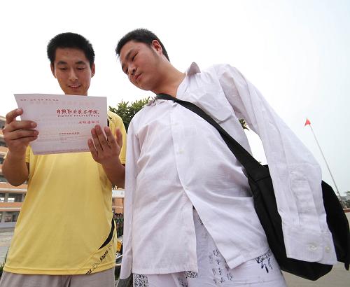 8月23日,无臂男孩戴军颂(右)和同学一起观看刚收到的新生录取通知书。新华社发(胡卫国 摄)