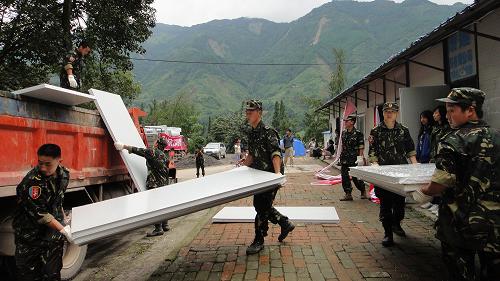 8月23日,部队官兵卸载刚从山外运输到绵竹市清平乡的板房材料,用于搭建板房学校。临近开学,四川省绵竹市清平乡干部群众在原乡政府的临时办公地点平整出900平方米的场地,用于搭建活动板房供学生上课。自8月23日凌晨汉清路抢通后,各种板房材料陆续运抵清平乡,工人们加班加点平整土地,安装板房,确保开学时全乡学生如期入学。新华社发(王平 摄)