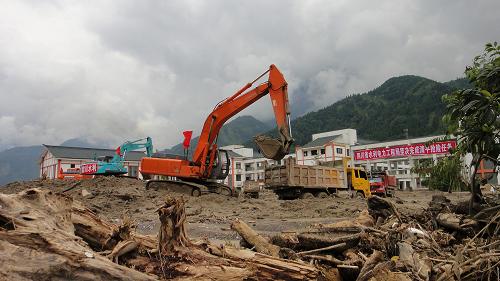 8月23日,在洪灾过后的绵竹市清平乡清平小学,四川水利电力工程局的车辆在清理操场上的泥石流淤泥、淤砂等杂物。新华社发(王平 摄)