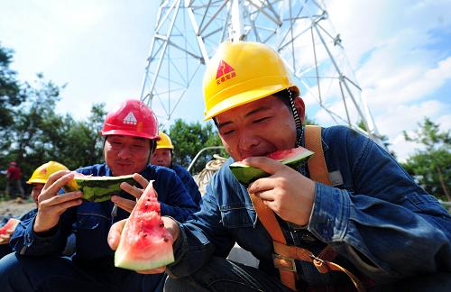 7月4日,在安徽省池州市里山乡的220千伏枫观线工地,安徽送变电工程公司的施工人员在铁塔下吃西瓜解暑。新华社发(郑贤列 摄)