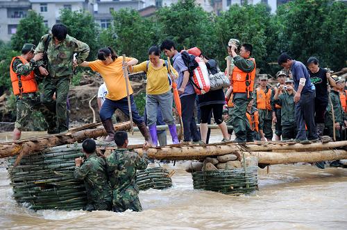 6月26日,被困宝庄村村民通过临时便桥转移。当日,在武警福建总队官兵及当地干群的协力救援下,福建顺昌县元坑镇宝庄村400多名受困群众通过临时搭建的便桥安全转移。至此,福建受洪涝灾害被困时间最长、救援任务最艰巨、救助条件最恶劣的“孤岛”宝庄村被“攻下”。 元坑镇宝庄村,位于海拔1304米的宝山南侧。6月18日以来,宝庄村受特大暴雨冲袭,山洪、泥石流摧毁入村的道路和桥梁,电力、通讯中断,480多名村民被困,其中有5名孕妇。新华社记者 姜克红 摄