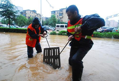 7月14日,在九江市庐山区十里大道,九江市政公司的工作人员打开雨水井盖,加快积水排放速度。自13日中午开始,江西九江市区遭受暴雨袭击,据江西省气象部门发布的信息,7月13日12时至14日12时,江西九江市区的累计降雨量达到106毫米,部分地区内涝严重,给交通和市民生活带来不便。新华社发(胡国林 摄)