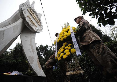 12月13日,部队新兵代表向“侵华日军南京大屠杀中山码头遇难同胞纪念碑”献花篮。当日,南京各界群众集会悼念侵华日军南京大屠杀30万同胞遇难73周年。在南京下关“侵华日军南京大屠杀中山码头遇难同胞纪念碑”前的分会场,来自各单位和街道社区的机关干部、市民群众、部队官兵及大屠杀幸存者代表一同举行悼念仪式,凭吊遇难同胞。新华社记者 孙参 摄