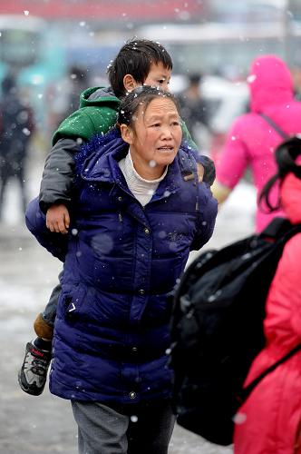 1月19日,在贵阳火车站广场上,一位母亲背着孩子准备进站.